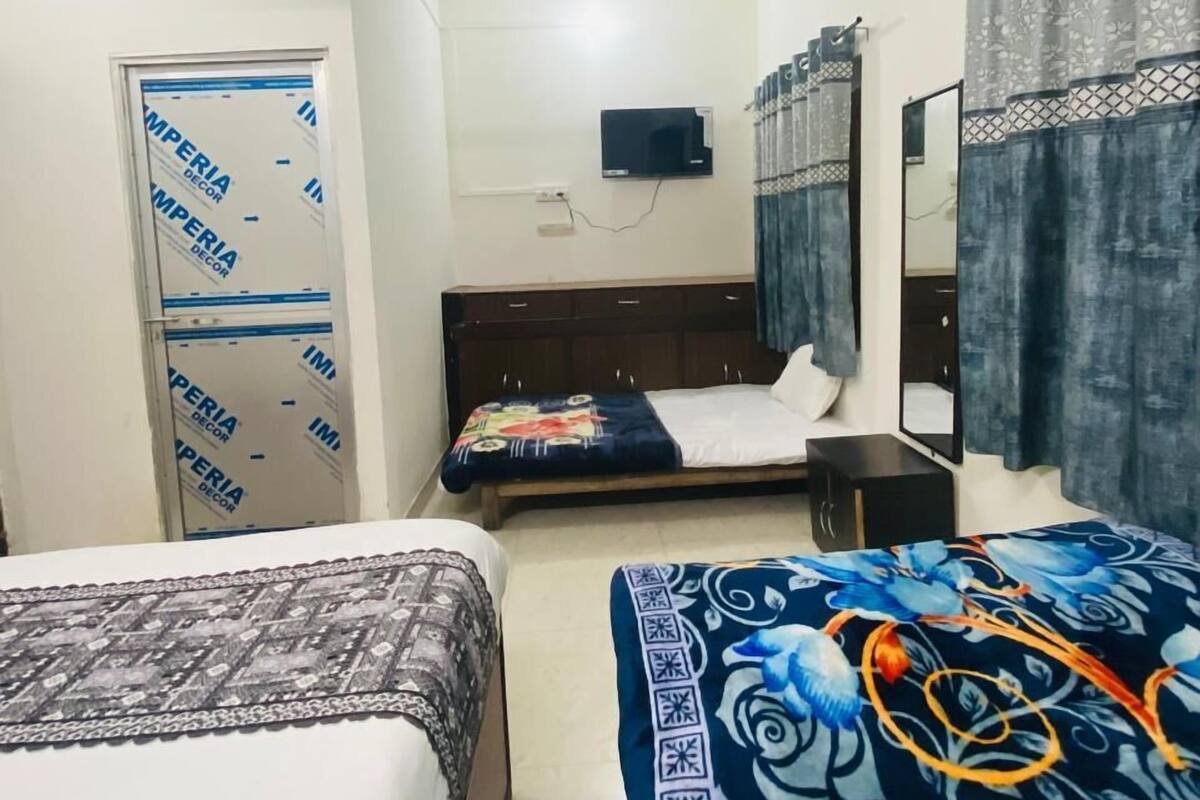 Habitación de hotel con dos camas, ventilador de techo, televisión y armario.