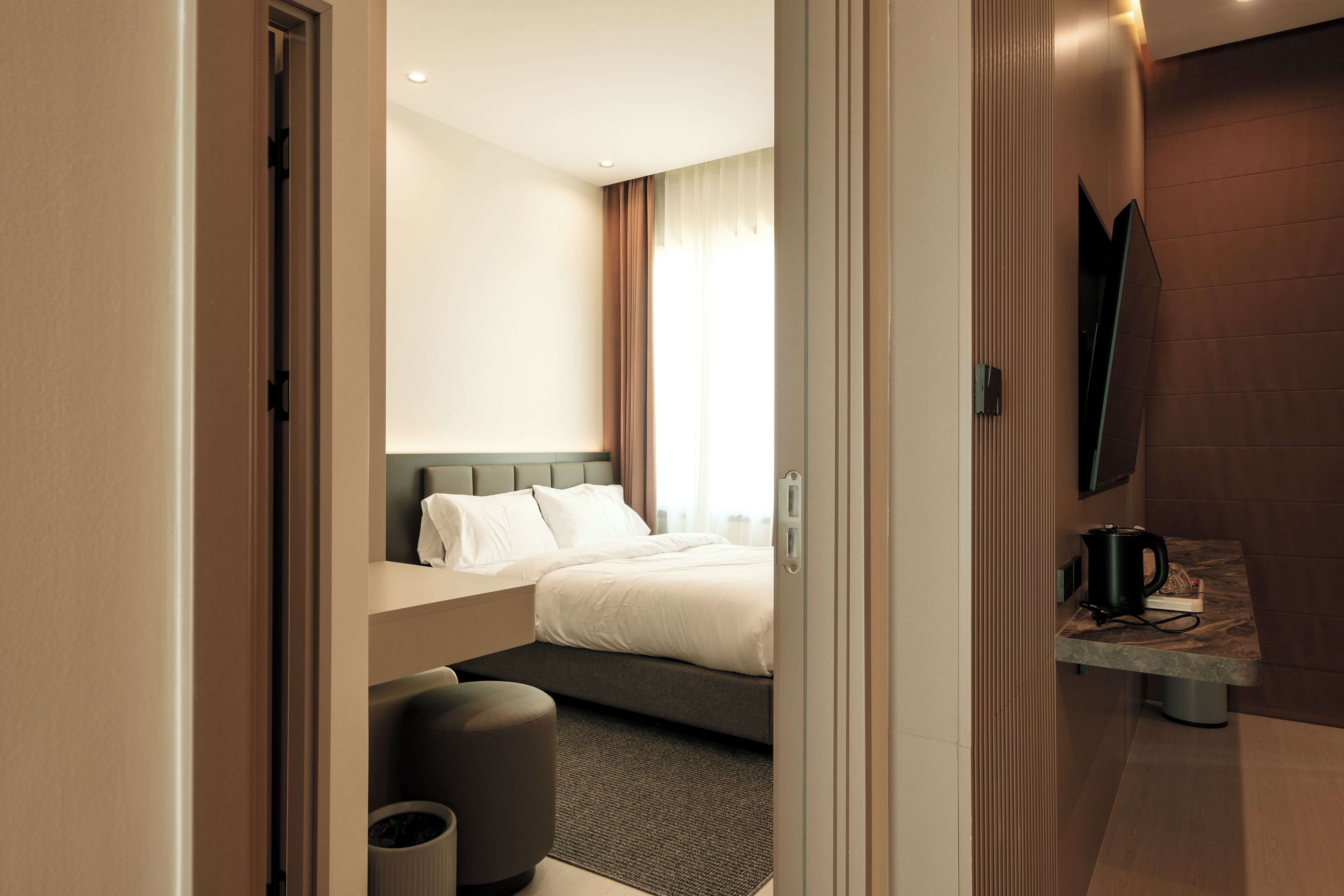 A modern hotel room with a bed, a seating area, a coffee table, and a television.