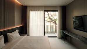 A modern hotel room with a large bed, a desk, a flat-screen TV, and a balcony with a view of the outdoors. - AFTER RAIN HOTEL (Chiang Mai)