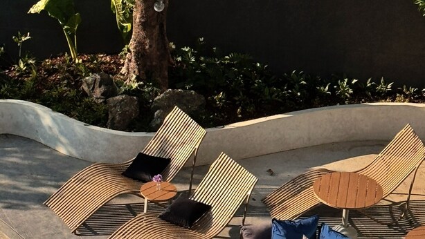 A poolside area with lounge chairs, a round seating area, and a pool. - AFTER RAIN HOTEL (Chiang Mai)