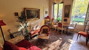 A cozy living room with a sofa, armchairs, a dining table, and a chandelier. - Wake up beside Napoleon (Paris)