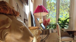 A room with a lion statue, a red cushioned bench, a patterned rug, a table with a lamp, and a chair. - Wake up beside Napoleon (Paris)