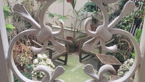 A wrought iron gate with intricate designs, leading to a patio area with a table and chairs, surrounded by potted plants and a small garden. - Wake up beside Napoleon (Paris)