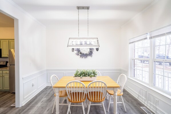 A dining room with a wooden table, white chairs, and a hanging light fixture. - Spacious & Comfortable Home -
Boiling Springs, SC (Boiling Springs)
