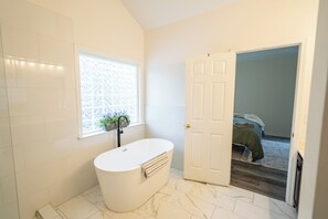 A bathroom with a freestanding bathtub, a window with a view, and a door leading to a bedroom. - Spacious & Comfortable Home -
Boiling Springs, SC (Boiling Springs)