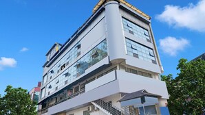 A multi-story building with a modern architectural design, featuring large windows and a prominent corner structure. - Townhouse City Center Kushal Nagar (Somvarpet)