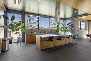 Une cuisine moderne dotée d’un îlot central, de grandes fenêtres et de plantes en pot.