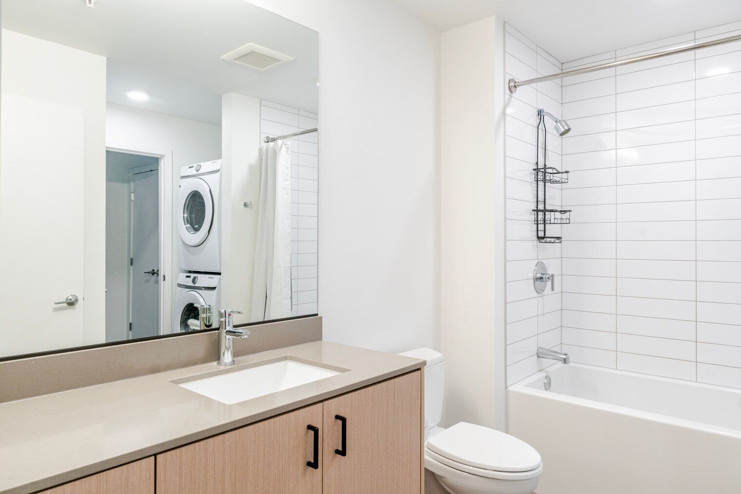 A modern bathroom with a sink, mirror, toilet, and a shower area.