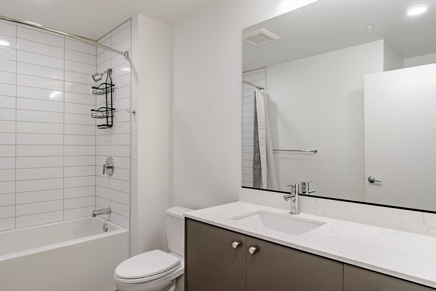 A modern bathroom with a bathtub, toilet, and vanity with a sink.