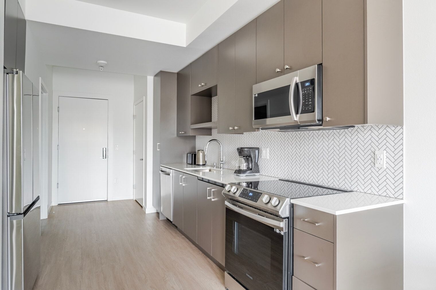 Una cocina moderna con electrodomésticos de acero inoxidable, un salpicadero con estampado de espiga y un diseño minimalista.