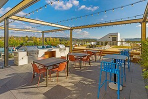 En udendørs terrasse med grill, siddepladser og lyskæder.