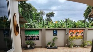 A courtyard with a tiled floor, potted plants, and a wall with a painting. - Pembeni River House (Arusha)