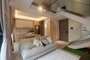 Una sala moderna con un sofá, una mesa de comedor y una zona de cocina al fondo.