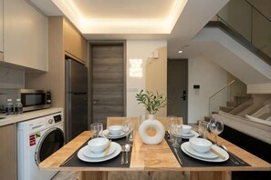 Een moderne keuken met een eethoek, een wasmachine en een trap.