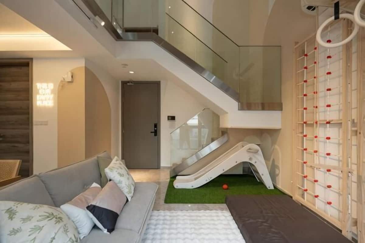 Un interior modern amb una escala, un tobogan, un sofà i una paret amb decoracions circulars.
