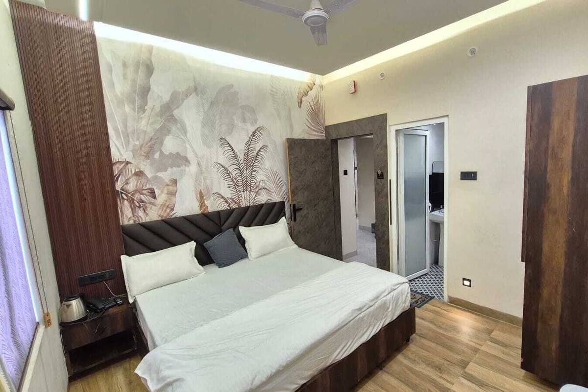 A modern bedroom with a large bed, a wardrobe, a bathroom with a mirror, and a ceiling fan.