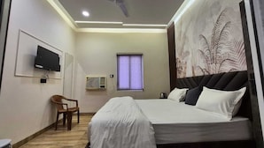 Una camera da letto con un letto, una TV a parete, una finestra con tende e una ventola a soffitto.