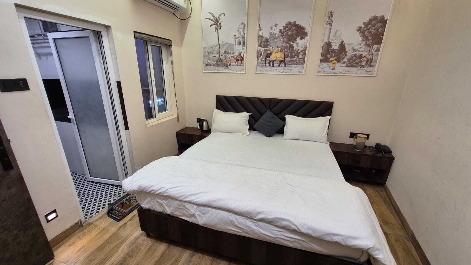 Une chambre à coucher avec un grand lit, deux tables de chevet, une fenêtre et une porte.