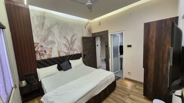 Una camera da letto moderna con un letto grande, un armadio, una televisione e l'ingresso del bagno.