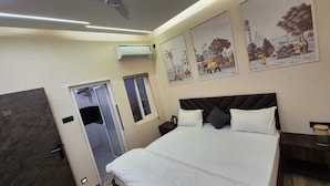 Una camera d'albergo moderna con un letto grande, un armadio, una finestra piccola e decorazioni murali raffiguranti scene storiche.