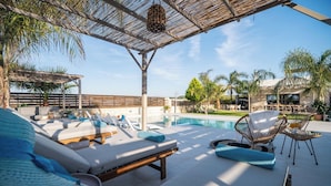 Et poolområde med liggestole, en pool og en pergola.