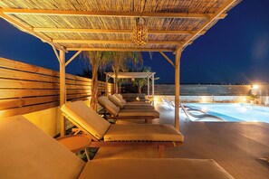 Un espace extérieur abrité avec des fauteuils confortables et une piscine.