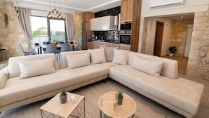 En moderne stue med en beige hjørnesofa, et træ sofabord og et spiseområde med bord og stole.