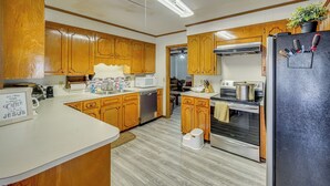 A kitchen with wooden cabinets, a microwave, a refrigerator, and a sink. - Family Home w/ Yard - 5 Mi to Jackson State Campus (Jackson)
