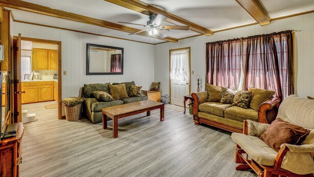 A living room with a wooden ceiling, a ceiling fan, a wooden coffee table, two sofas, a chair, and a dining table. - Family Home w/ Yard - 5 Mi to Jackson State Campus (Jackson)
