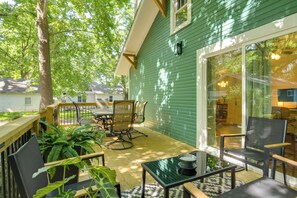 A green house with a patio, a dining table, chairs, and a large window. - < 1 Mi to MSU! Updated Springfield House w/ Deck (Springfield)