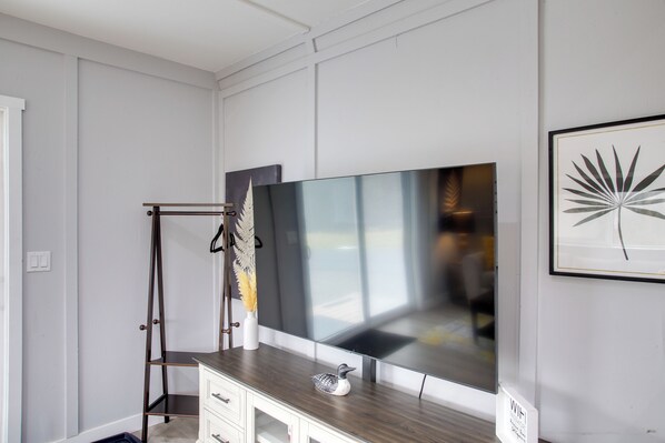 A modern room with a large flat-screen TV mounted on a wooden cabinet, a ladder, and a framed artwork on the wall. - Bougie Barn 5 mi to Silverwood theme park! (Athol)