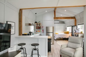 Un intérieur moderne comprenant une cuisine, un coin repas et une chambre avec une grande fenêtre.