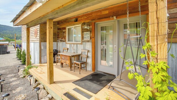 Una baita di legno con un portico, un tavolo, sedie e un cartello che dice 'GUEST HOUSE'.