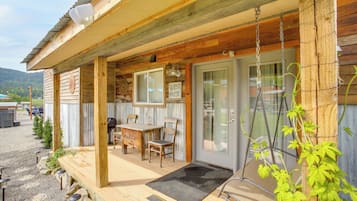 A wooden cabin with a porch, a table, chairs, and a sign reading 'GUEST HOUSE'.