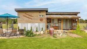Una casa a due piani con un patio, un vaso grande e mobili da esterno.