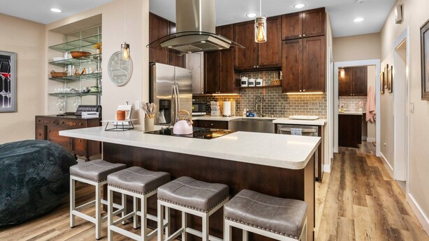 Une cuisine moderne dotée d’un îlot central, d’appareils électroménagers en acier inoxydable et de meubles en bois.