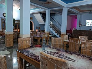 Ein geräumiger Saal mit hohen Decken und einer zentralen Treppe. Tische und Stühle sind für Sitzgelegenheiten angeordnet.