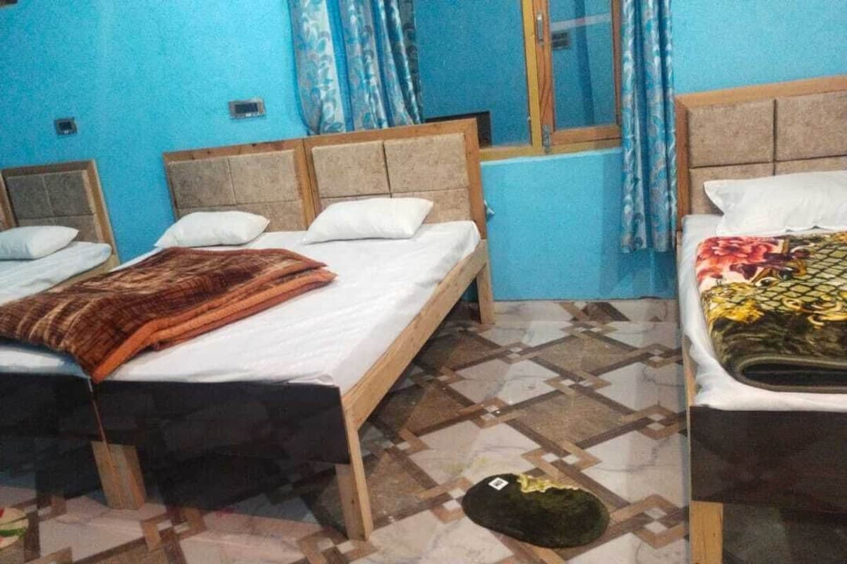 A room with two beds, each with wooden frames and white bedding. The room has a tiled floor with a geometric pattern.