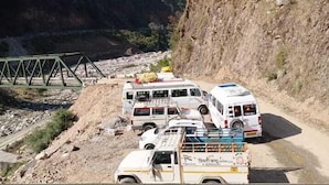 A group of buses parked on a dirt road beside a bridge. - Rishi River View (Rajgarhi)