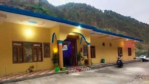 A building with a yellow facade, blue roof, and a small entrance with a sign. - Rishi River View (Rajgarhi)
