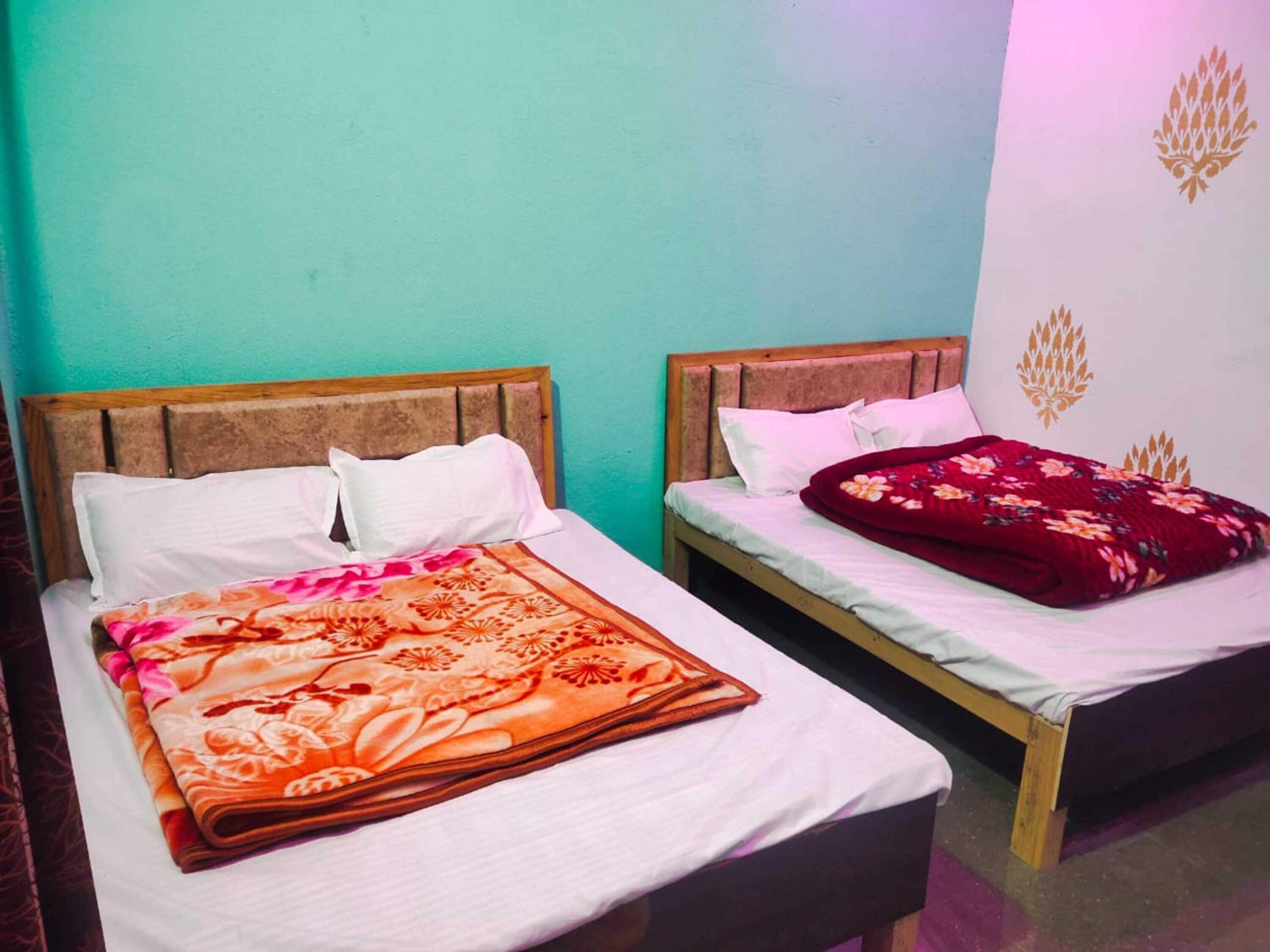 Two single beds with wooden headboards in a room with teal walls and decorative wall art.