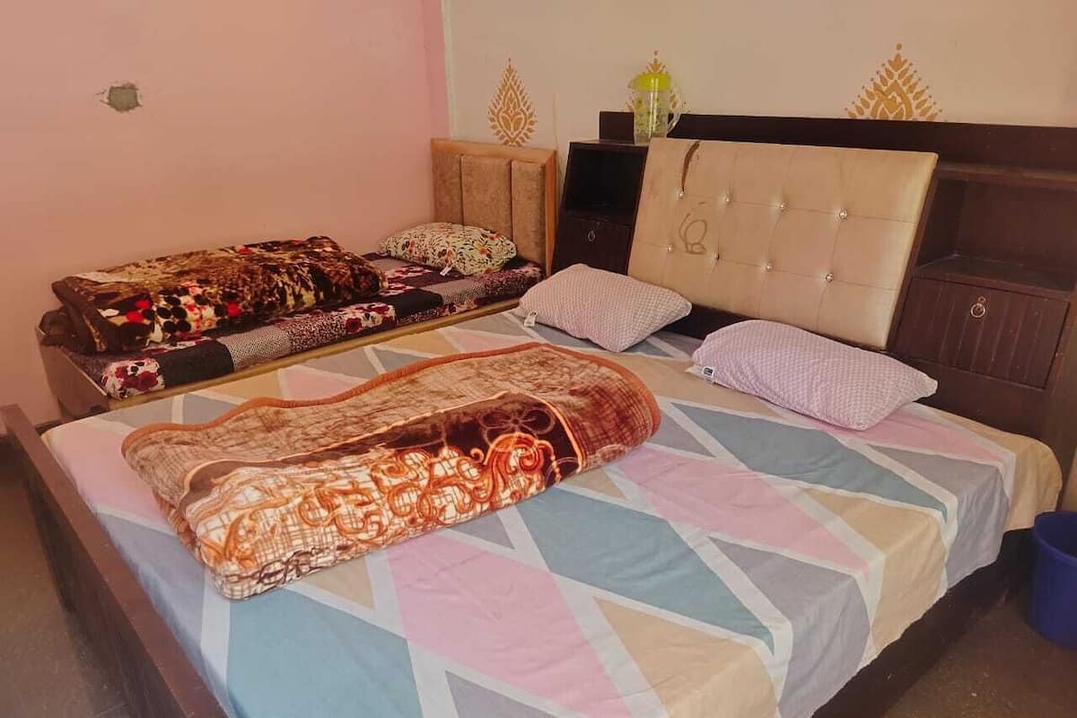 A bed with a patterned blanket, pillows, and a headboard.