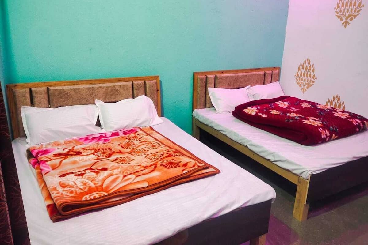 Two single beds with wooden headboards, white bedding, and a floral-patterned blanket on one bed.