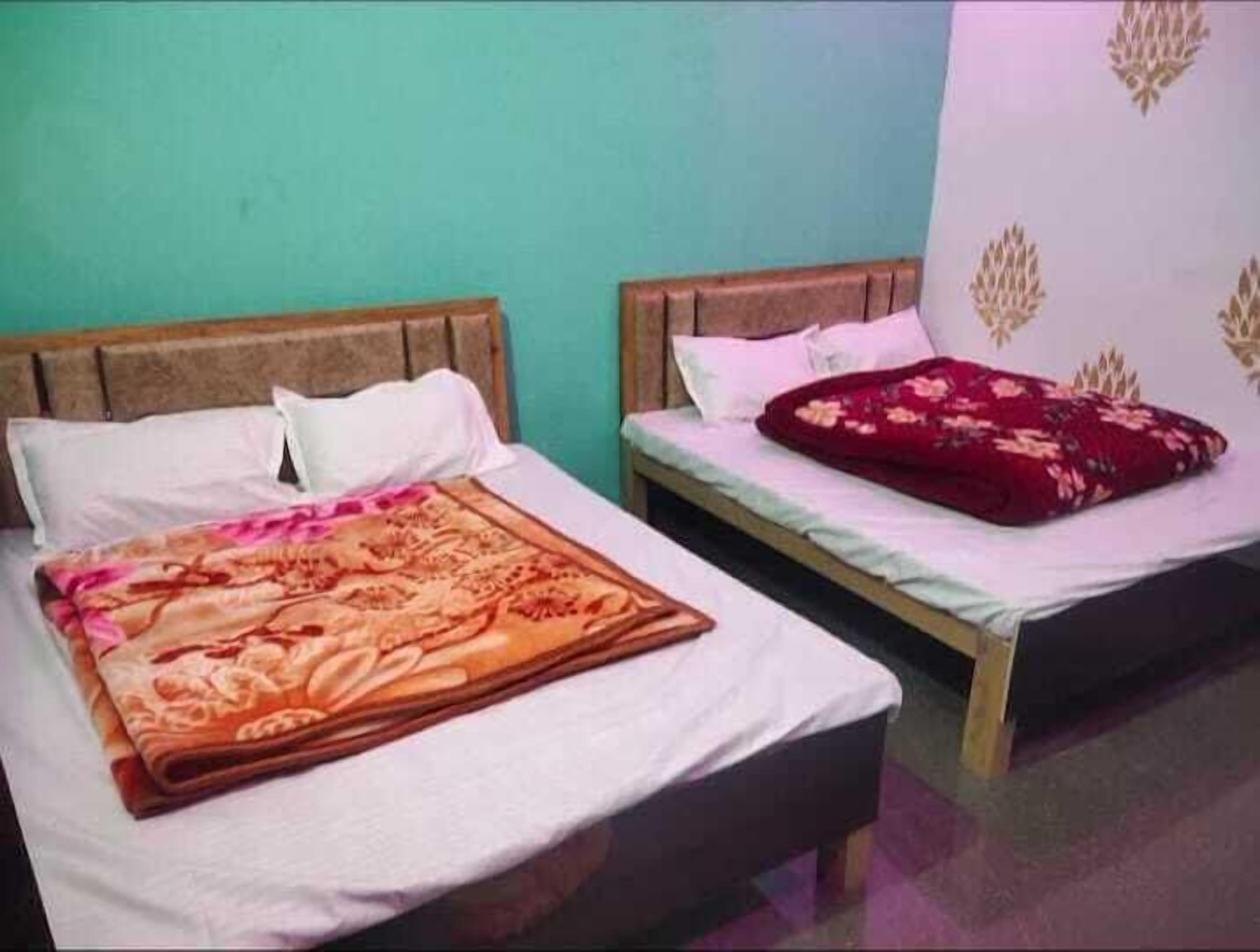 Two single beds with wooden headboards, white bedding, and a floral-patterned blanket on the left bed.