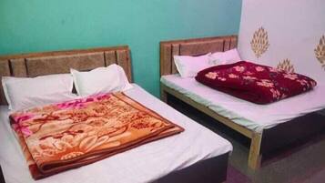 Two single beds with wooden headboards, white bedding, and a floral-patterned blanket on the left bed.