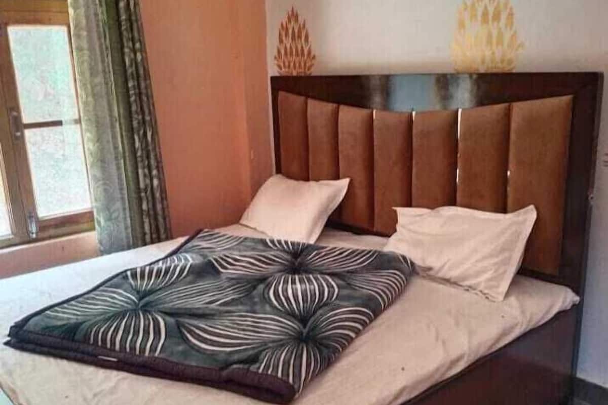 A bed with a patterned bedspread, a headboard, and two pillows.