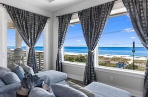 Una habitación con vista a la playa, un sofá y cortinas.