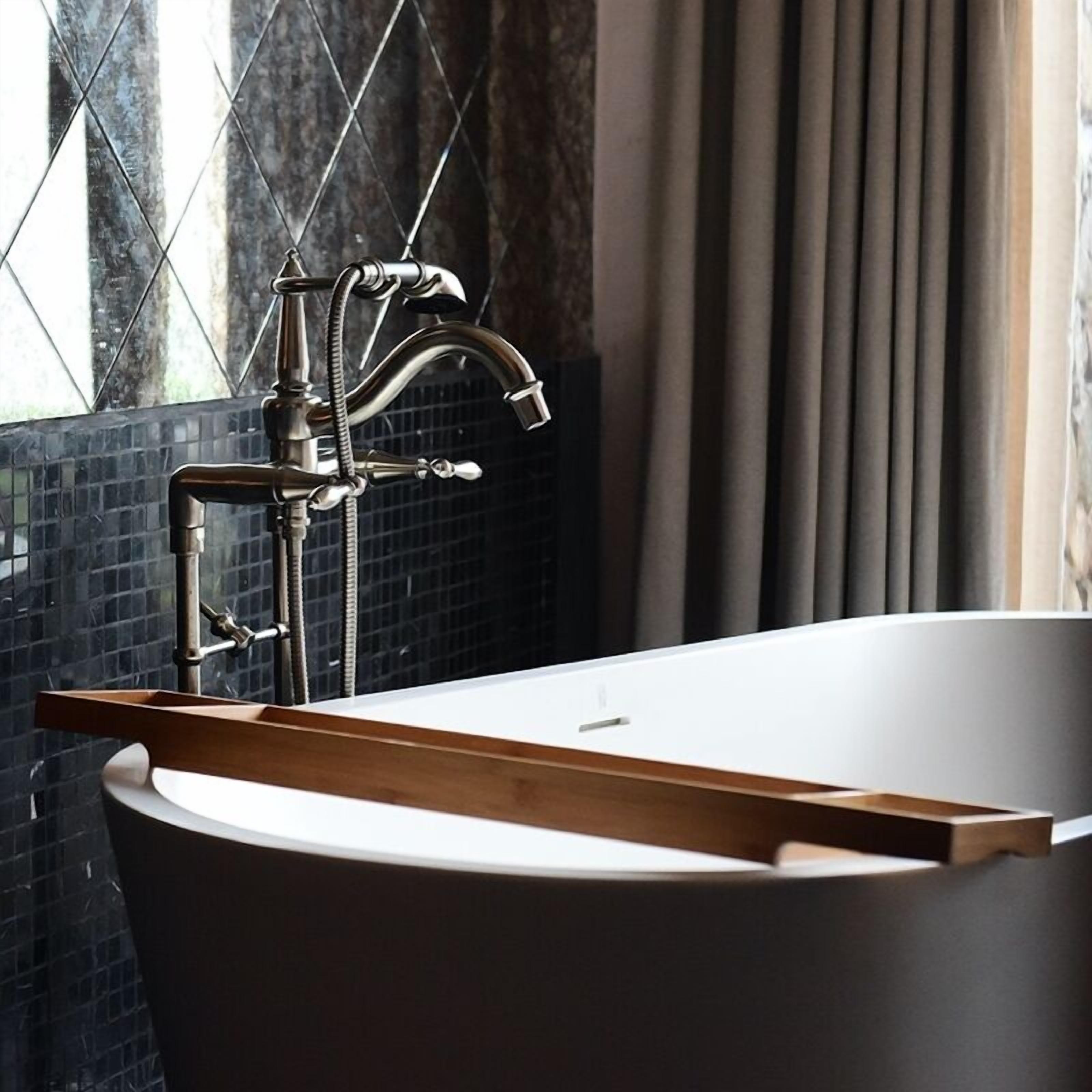 A modern bathroom with a freestanding bathtub, a visible showerhead, and a window with a view of the outside.