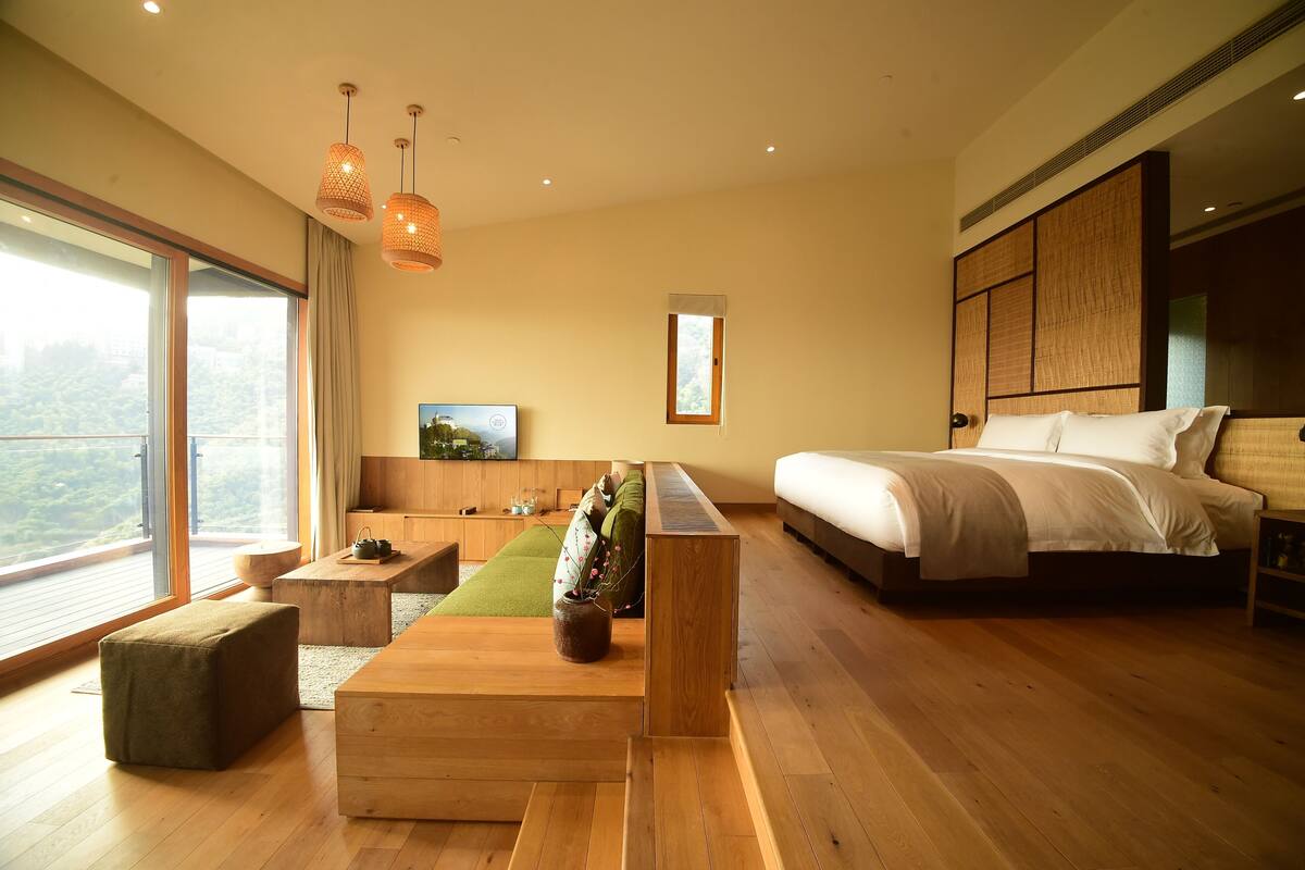 Un dormitorio moderno con una cama grande, un sofá, una mesa de centro y un televisor.