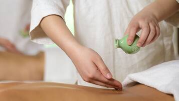 A person receiving a massage with a green bottle on their back.